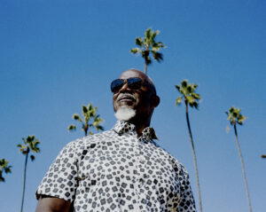 Photo of Karl Denson with blue sky and palm trees