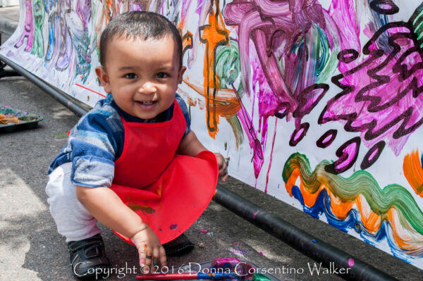 Cute baby with apron painting a mural