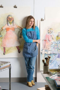 female artist standing in front of artwork
