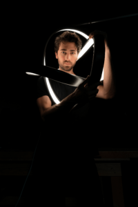 hispanic male artist standing behind light sculpture