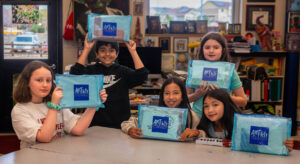 Photo of smiling students holding up art supplies