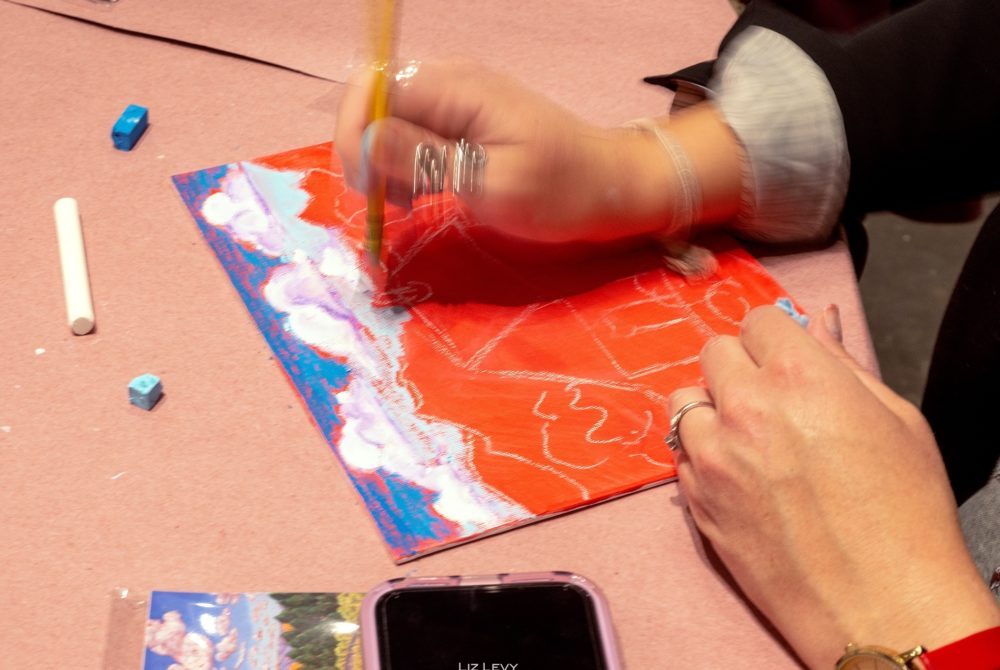 closeup of hands creating a pastel landscape art piece