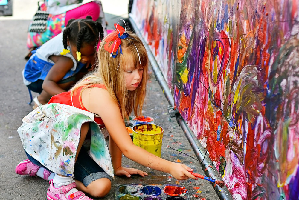 two girls adding paint to a mural